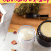 Homemade cannabis-infused balm in a small glass jar on a silver tray.