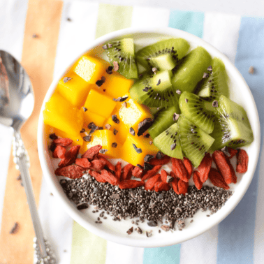 A picture of a white bowl with a cannabis-infused yogurt bowl topped with fruit.