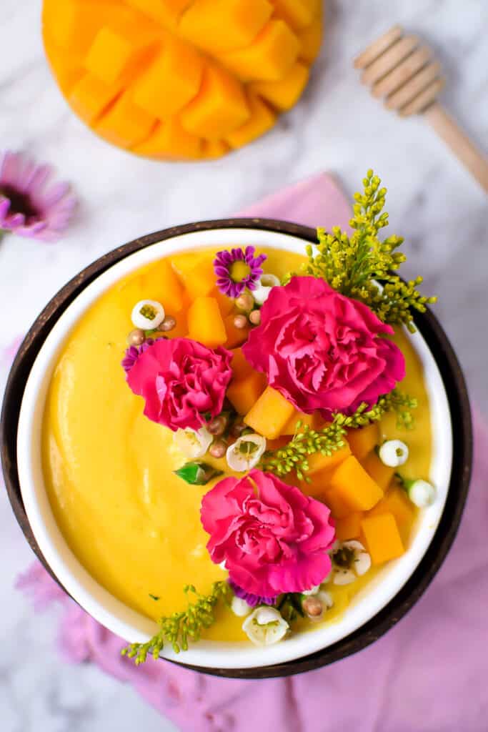 Springtime Mango Smoothie Bowl with Edible Flowers by Emily Kyle Nutrition