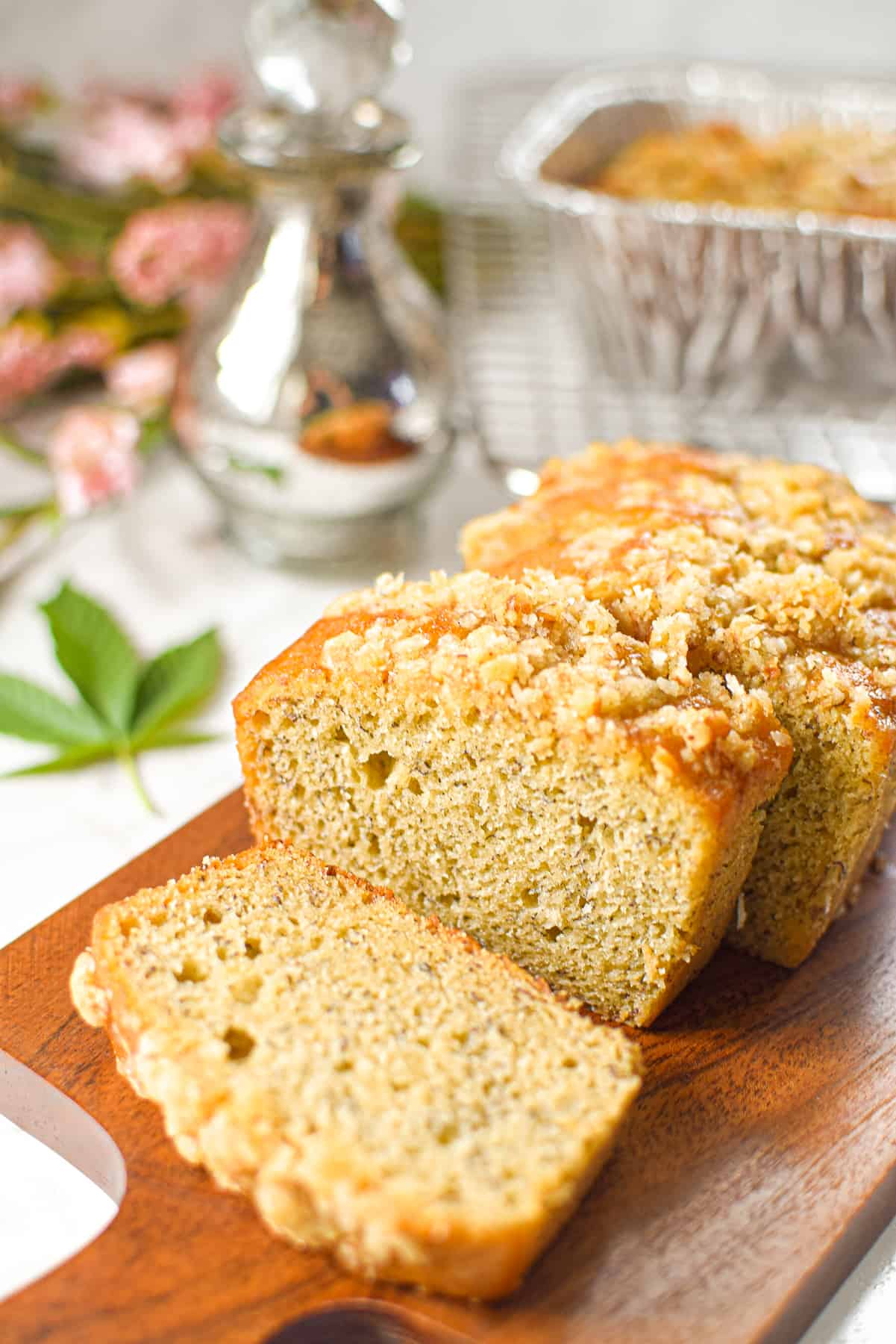 A photo of sliced cannabis banana bread on a cutting board with a cannabis leaf in the background