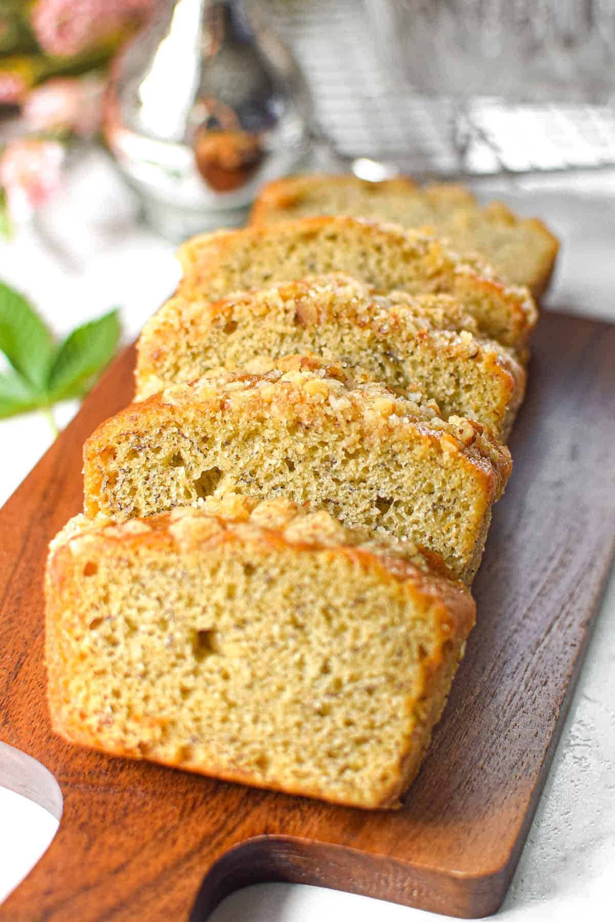 A photo of sliced cannabis banana bread on a cutting board with a cannabis leaf in the background