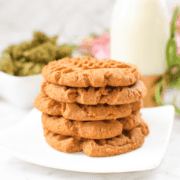 A white plate with a stack of cannabis peanut butter cookies