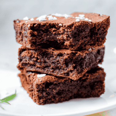 A white plate with three cannabis brownies stacked on top, garnished with a cannabis leaf