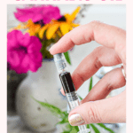 A hand holding a syringe full of a black substance known as Full Extract Cannabis Oil or FECO