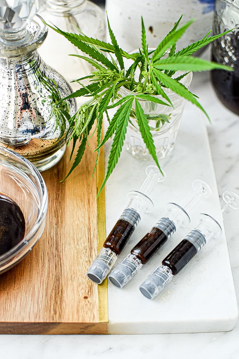 A white countertop with a white and wood cutting board topped with three FECO syringes 