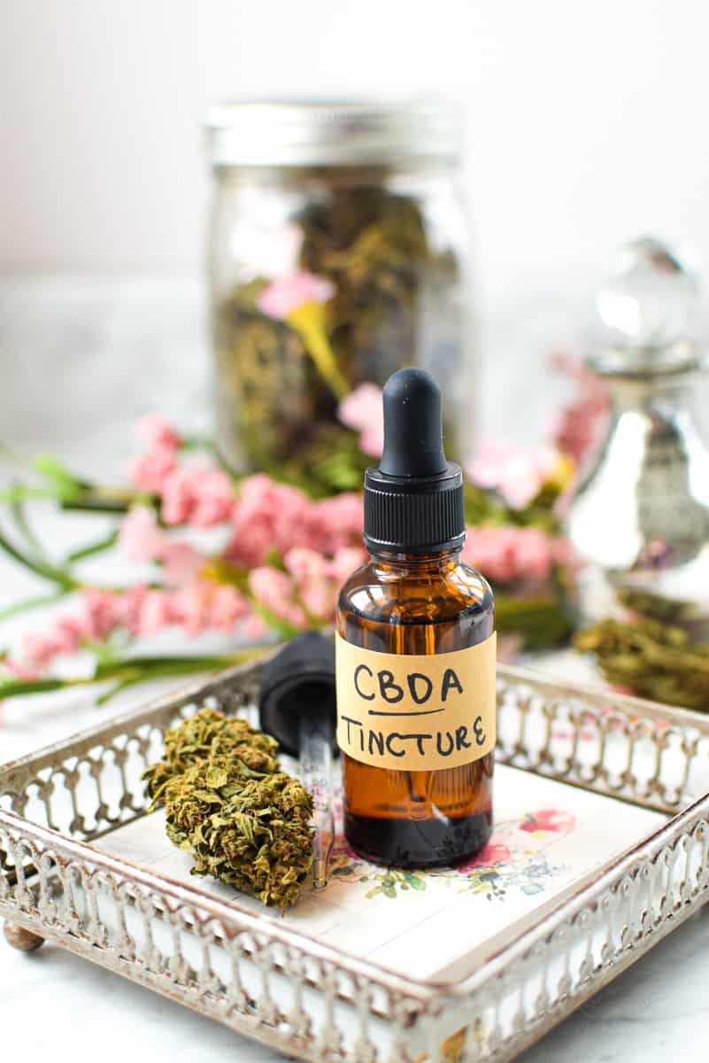 A white countertop with a brown tincture bottle labeled CBDA Tincture