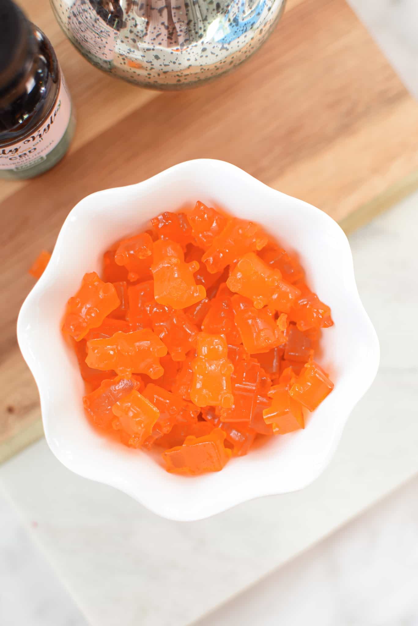 A picture of orange homemade CBD gummies in a white cup.