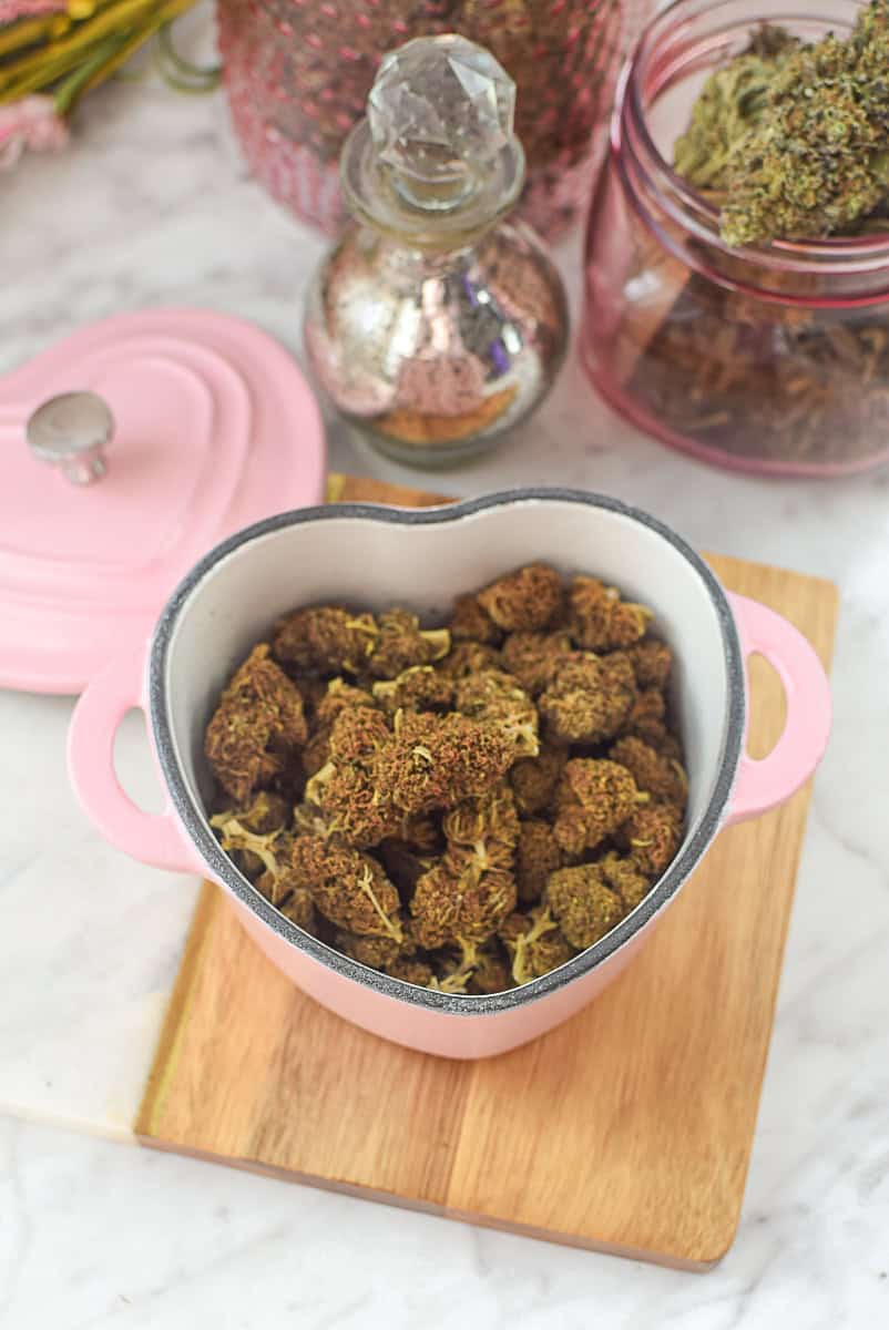 Decarboxylated cannabis buds in a heart-shaped pink bowl for edibles.