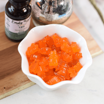 A picture of orange homemade CBD gummies in a white cup.