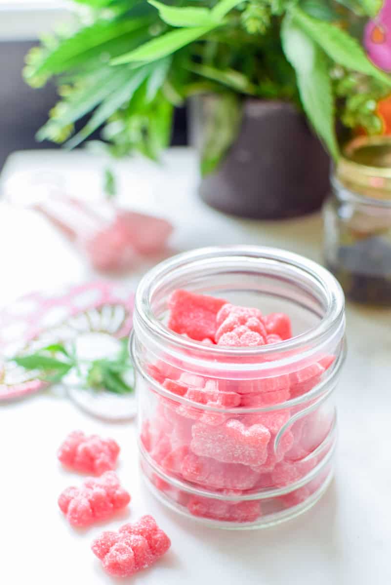 A picture of a container of pink gummies with a cannabis leaf in the background. 