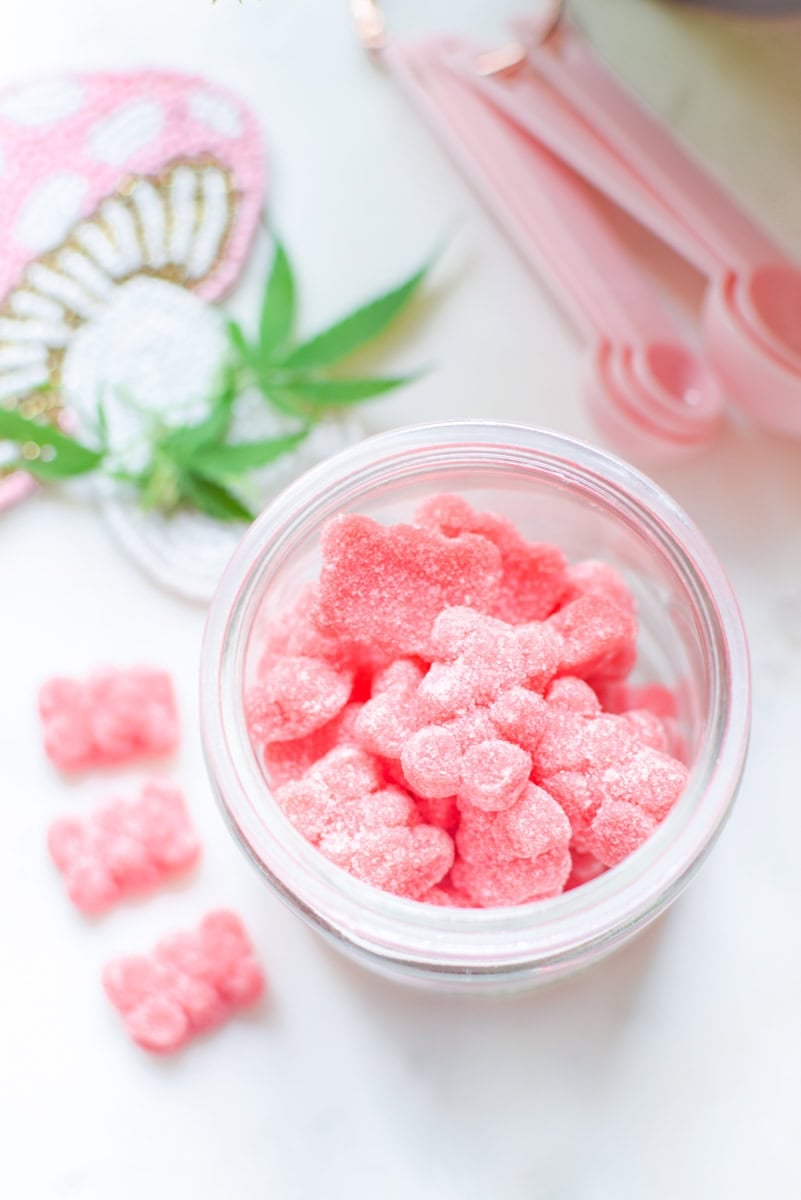 A picture of a container of pink gummies with a cannabis leaf in the background.