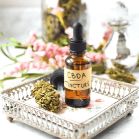 A white countertop with a brown tincture bottle labeled CBDA Tincture