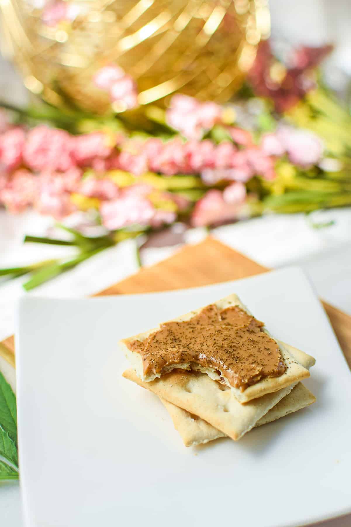 A picture of cannabis firecrackers, peanut butter and cannabis on top of a saltine cracker