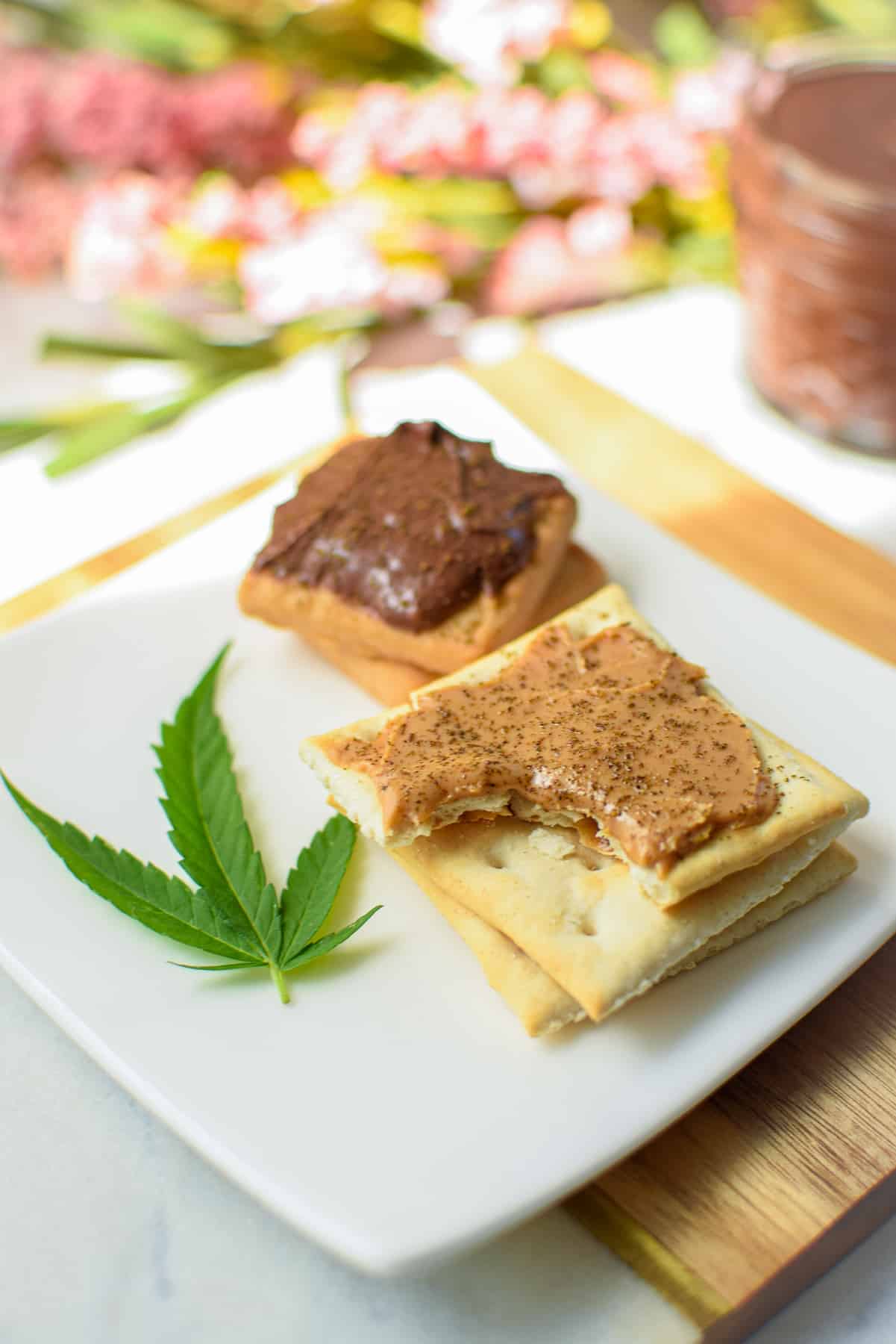 Saltine crackers topped with peanut butter and cannabis and cookies topped with Nutella and cannabis