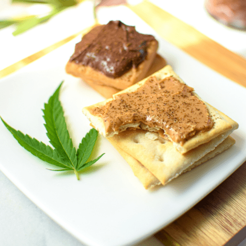 Saltine crackers topped with peanut butter and cannabis and cookies topped with Nutella and cannabis