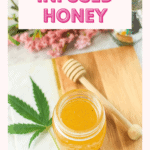 A finished image of cannabis-infused honey with pink flowers and a fresh cannabis leaf in the back, with a honey dobber about to be added to the jar.
