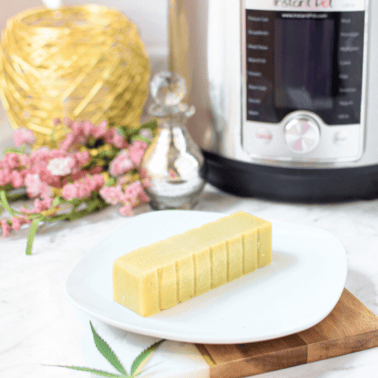 A picture of a stick of cannabutter on a white plate with an instant pot in the background.