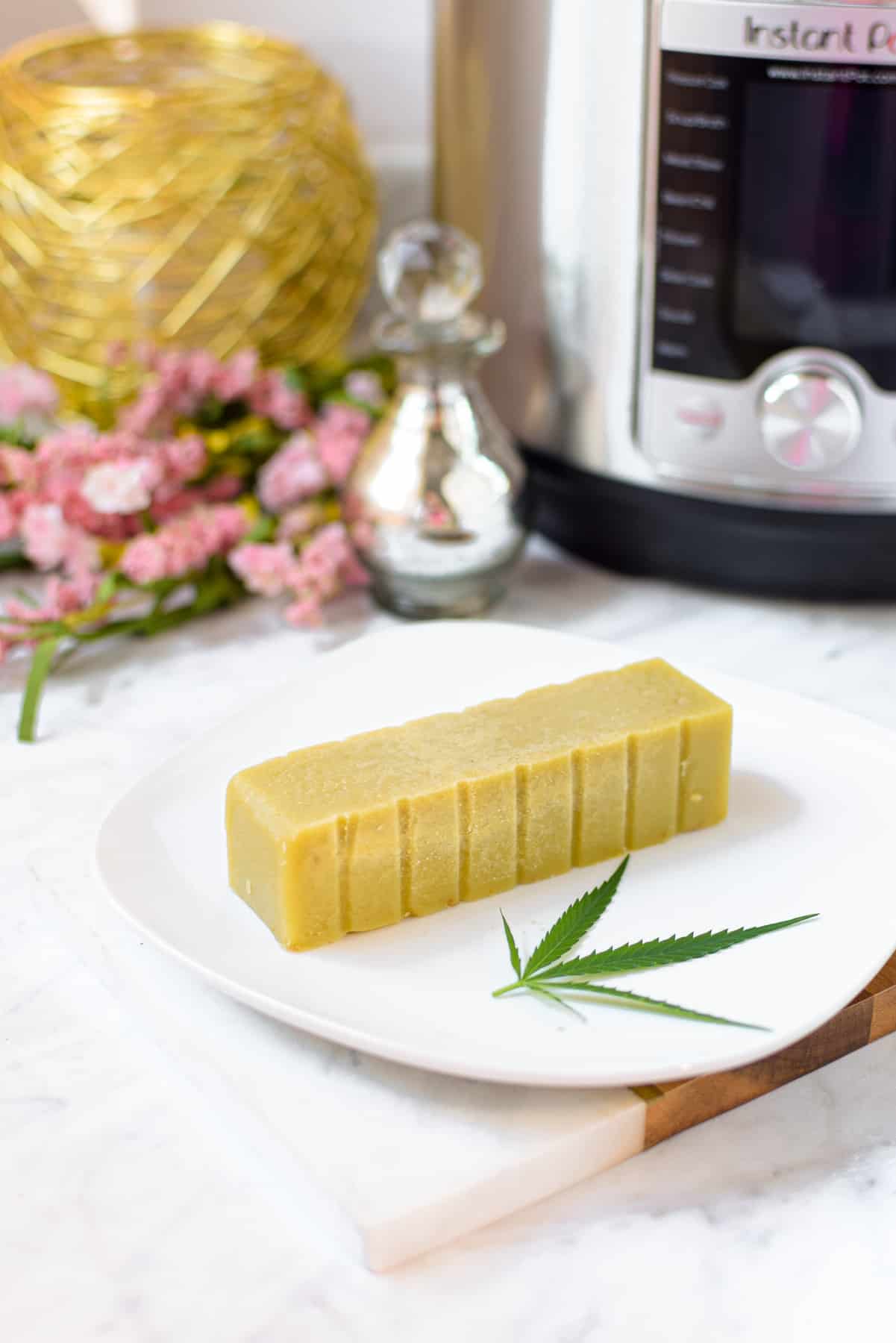 A picture of a stick of cannabutter on a white plate with an instant pot in the background 