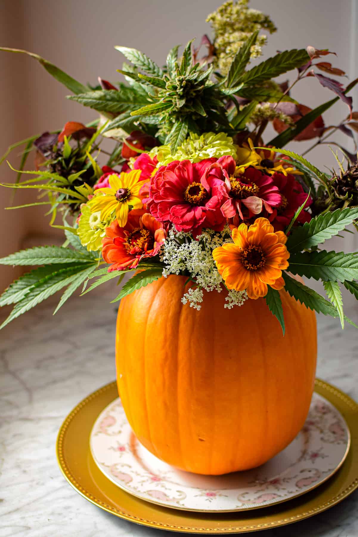 A pumpkin on a plate with flowers coming out the top to create a cannabis fall centerpiece