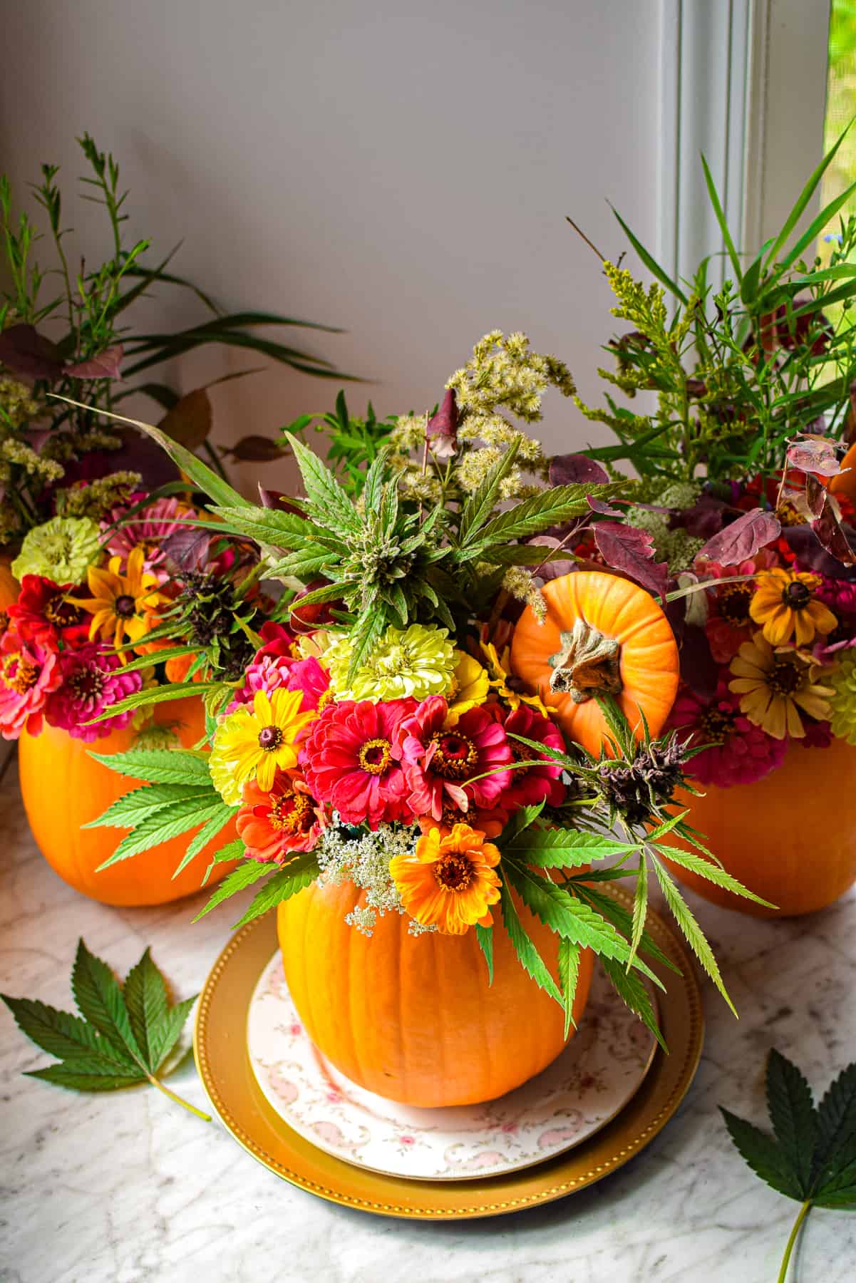 A pumpkin on a plate with flowers coming out the top to create a cannabis fall centerpiece
