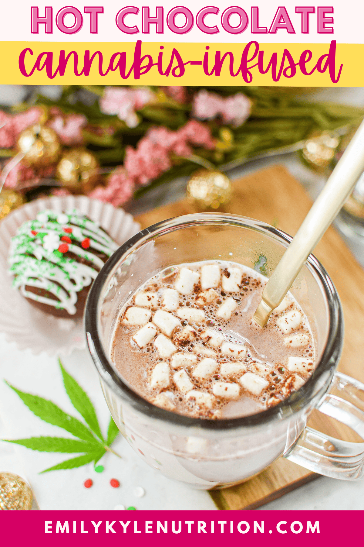 A white countertop with a cutting board topped with a clear mug full of cannabis hot cocoa with marshmallows, garnished with a cannabis leaf