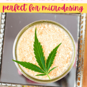 A white counter top with a cutting board with a mirrored tray topped with a mason jar full of cannabis salt, garnished with a cannabis leaf