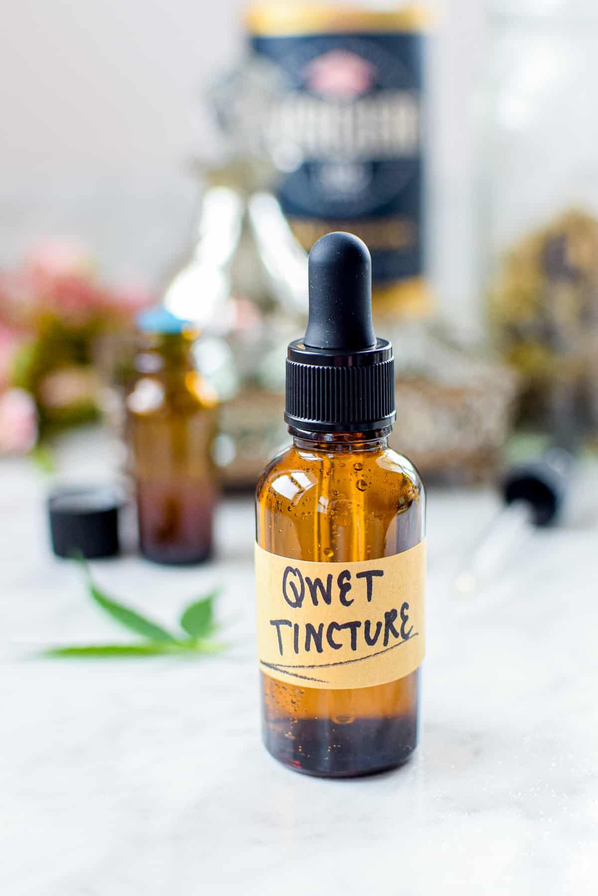 A white countertop with a brown tincture bottle labeled QWET Tincture
