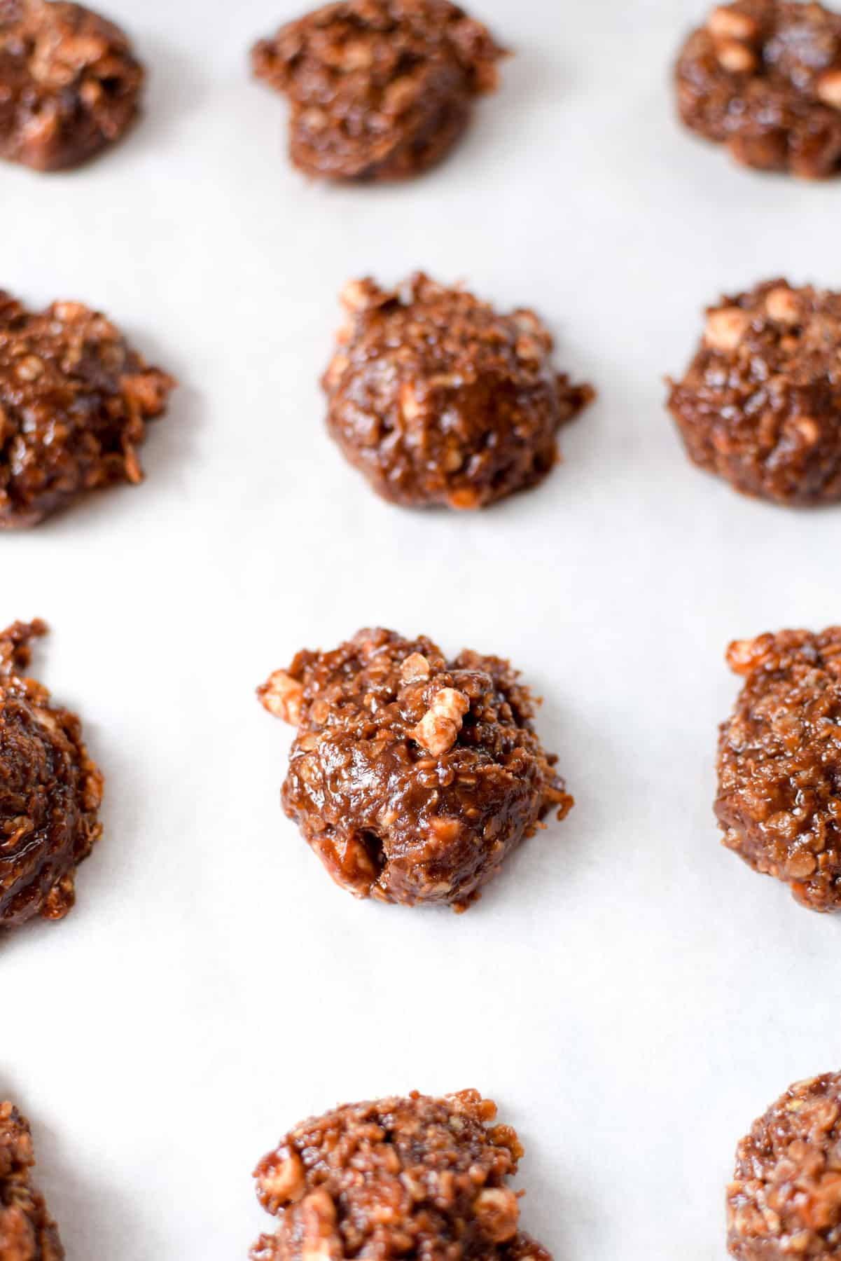 A white parchment lined baking sheet topped with individual no-bake rocky road cannabis cookies