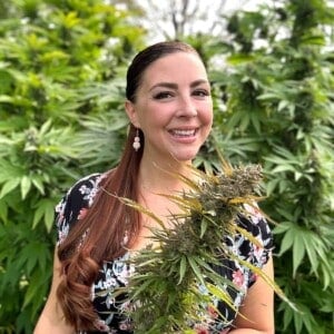 A picture of Emily Kyle holding a cannabis plant.
