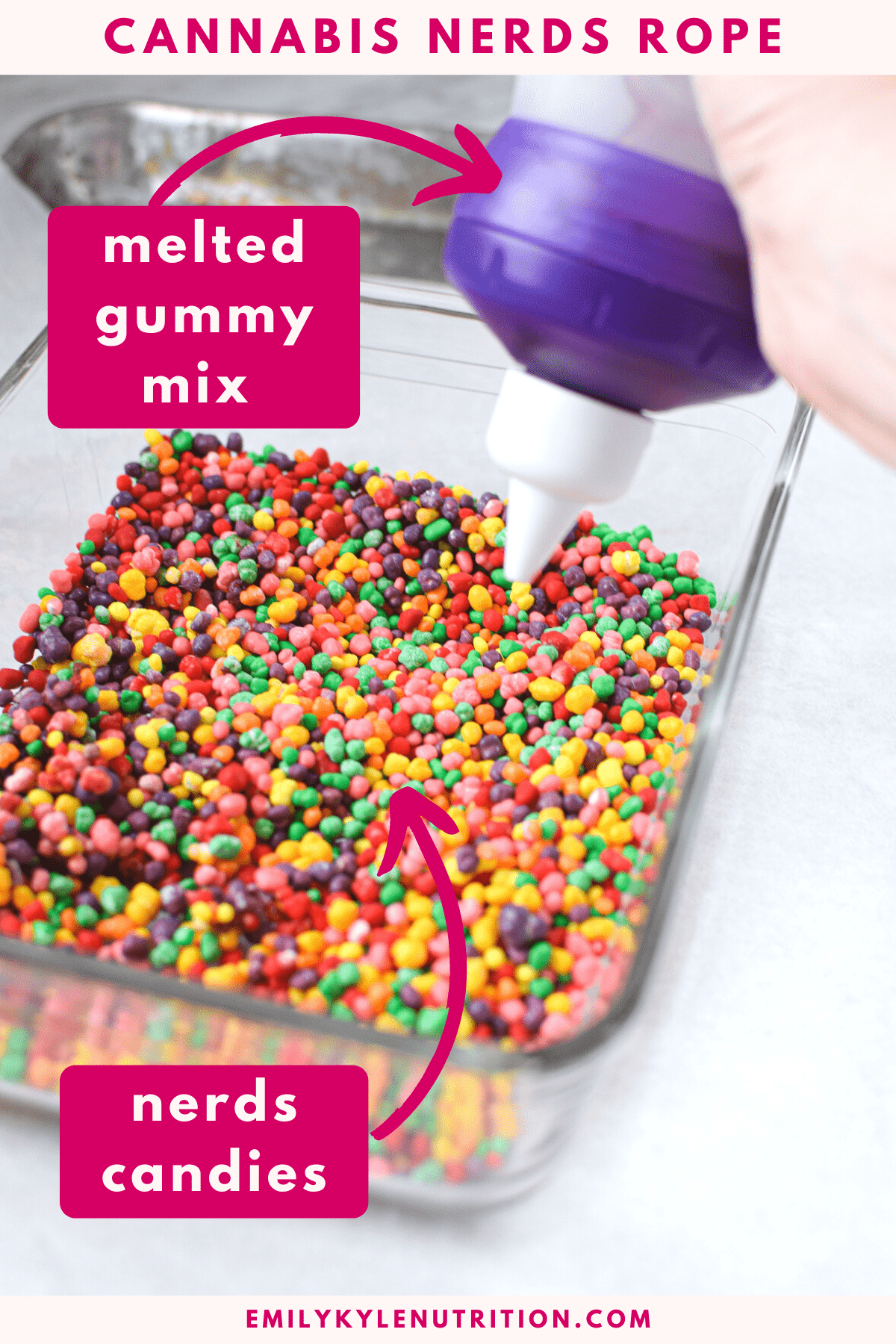 A bowl of nerds candies with a hand holding a squeeze bottle over top