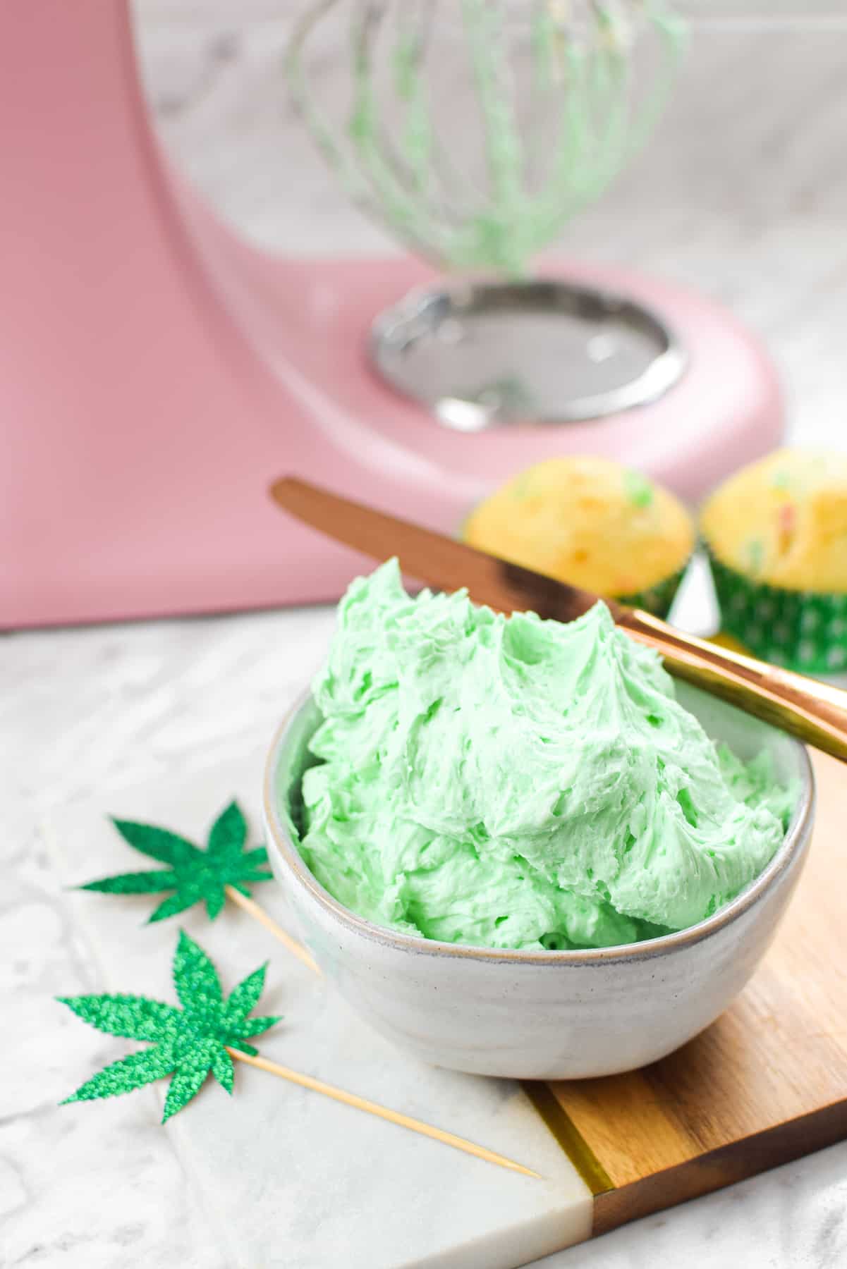 A white countertop with a bowl of green cannabis buttercream frosting