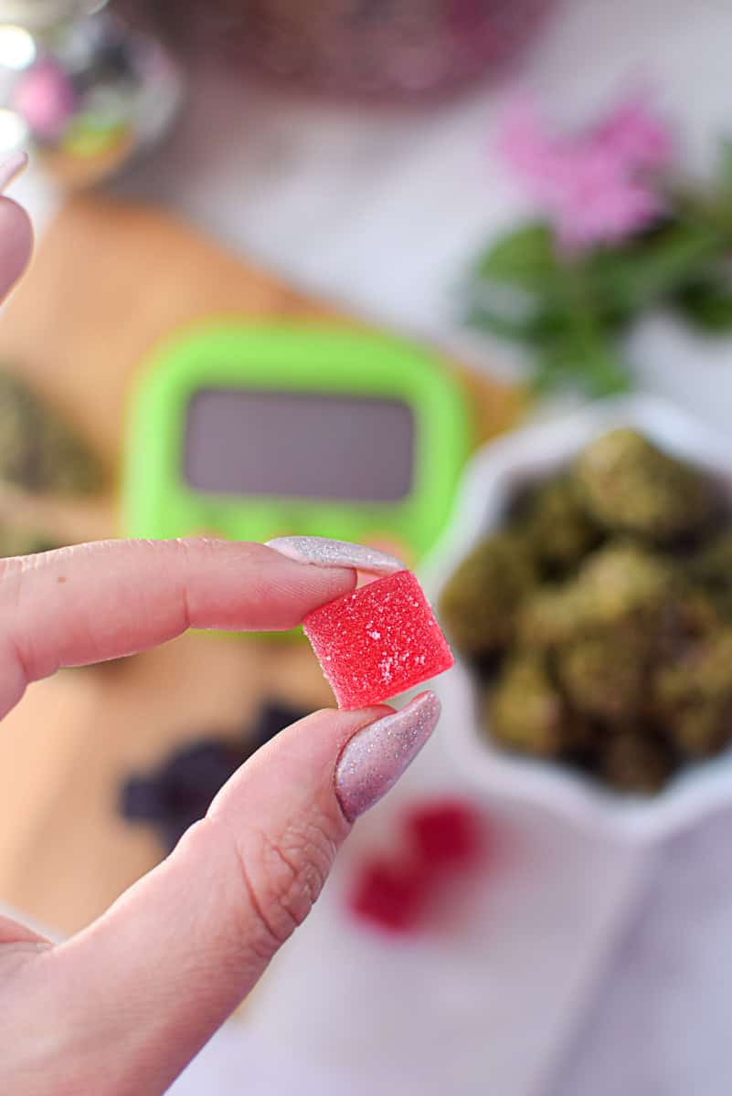 A picture of several different kinds of cannabis edibles, with a gummy in one hand.