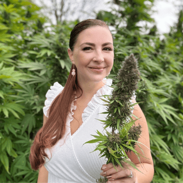 A picture of Emily Kyle with a female cannabis plant.