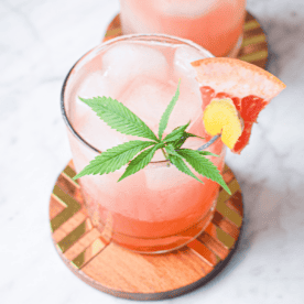 A picture of a glass of the prepared cannabis Paloma cocktail garnished with a cannabis leaf.