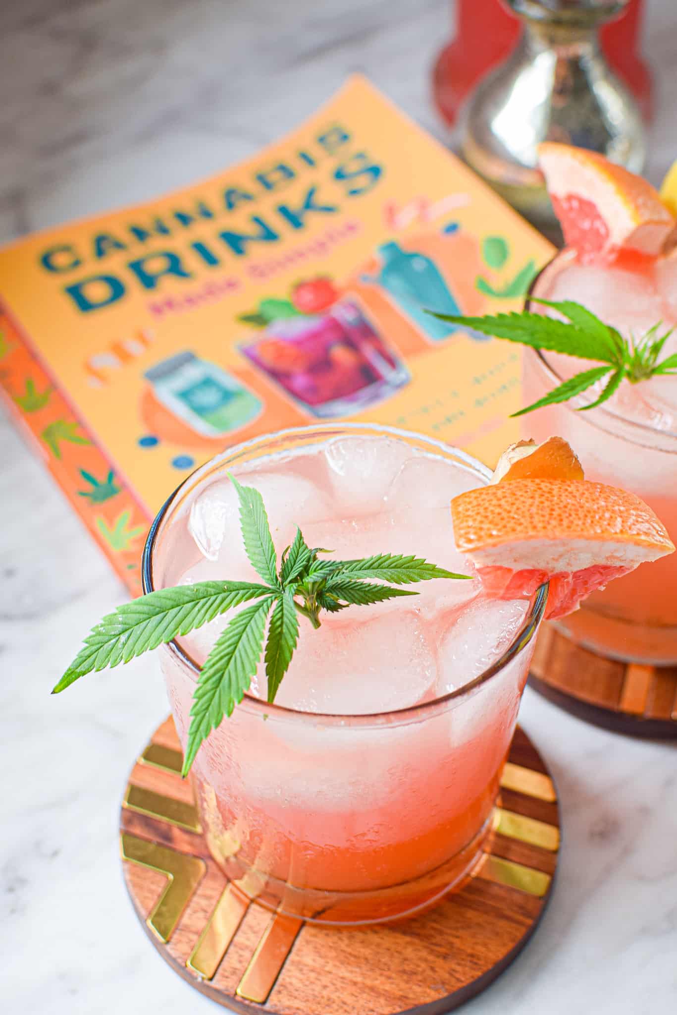 A picture of a glass of the prepared cannabis Paloma cocktail garnished with a cannabis leaf.