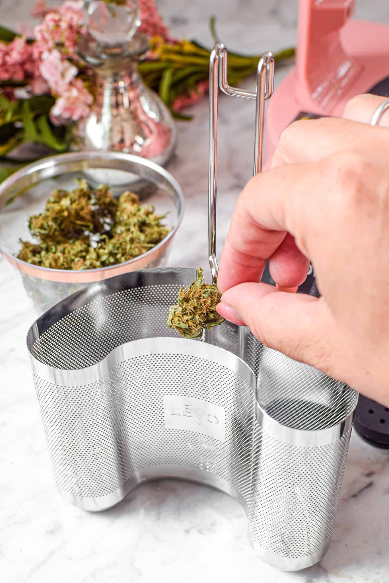 A picture of cannabis flower being placed in the pod for the LEVO machine.