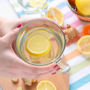 A picture of a clear mug full of lemon, ginger, honey and warm water.