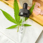 A picture of a cannabis tincture and a hand pulling out the dropper.