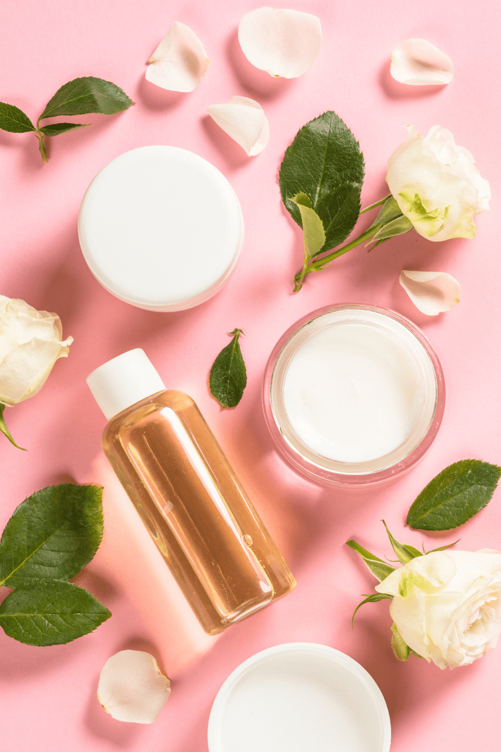 A picture of a pink background with roses, lotion, and oil.