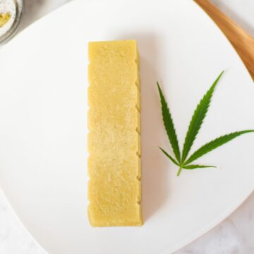 A picture of stovetop cannabutter made in a mason jar with a cannabis leaf on a white plate.