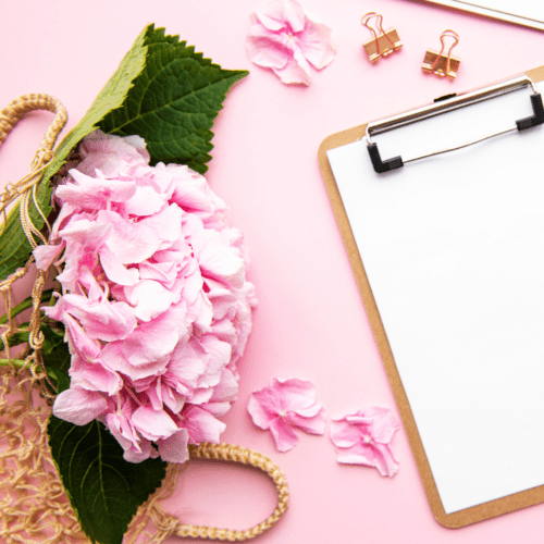 A picture of a pink desk with pink flowers and a white piece of paper on a clipboard.