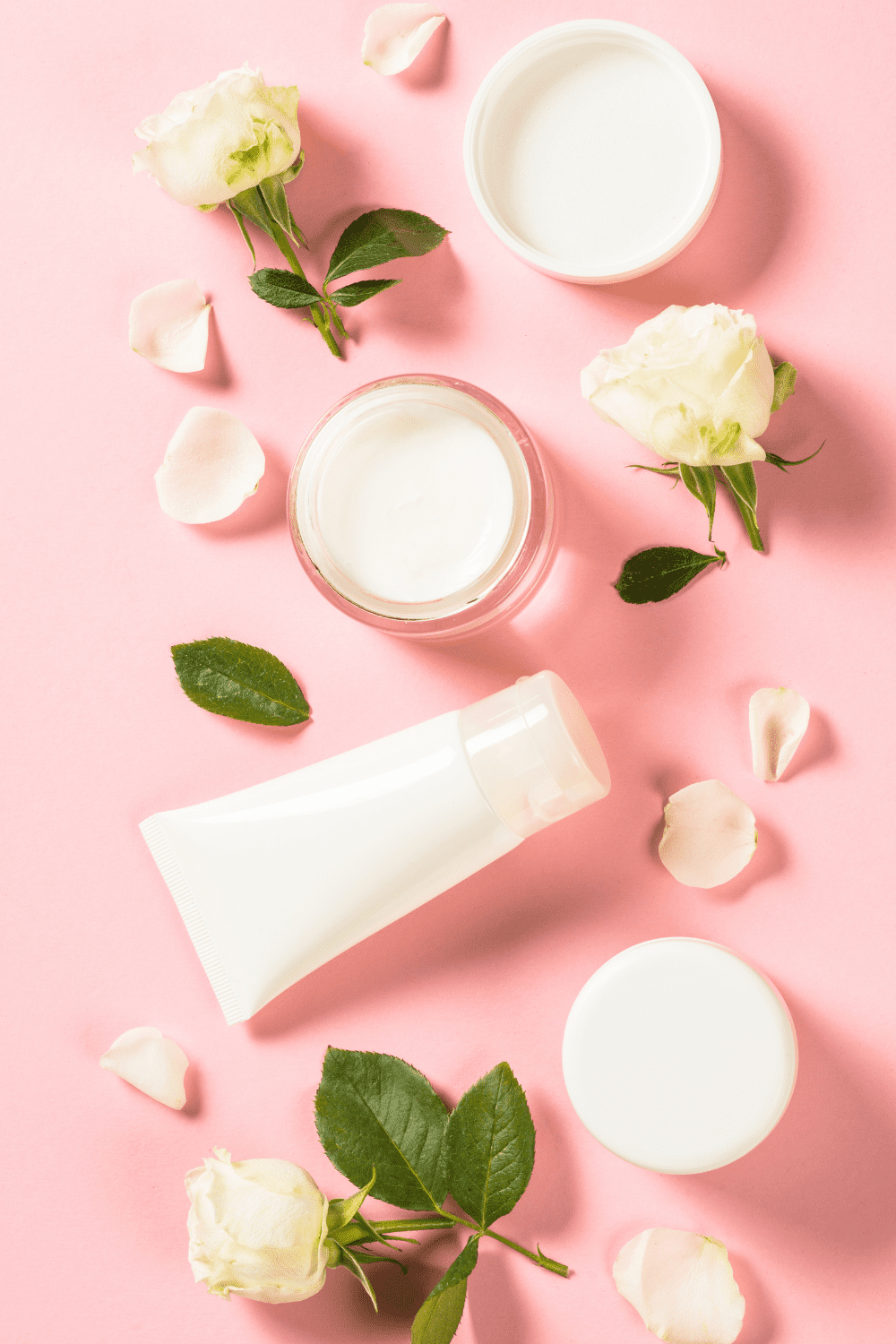 A picture of a pink background with roses, lotion, and oil.