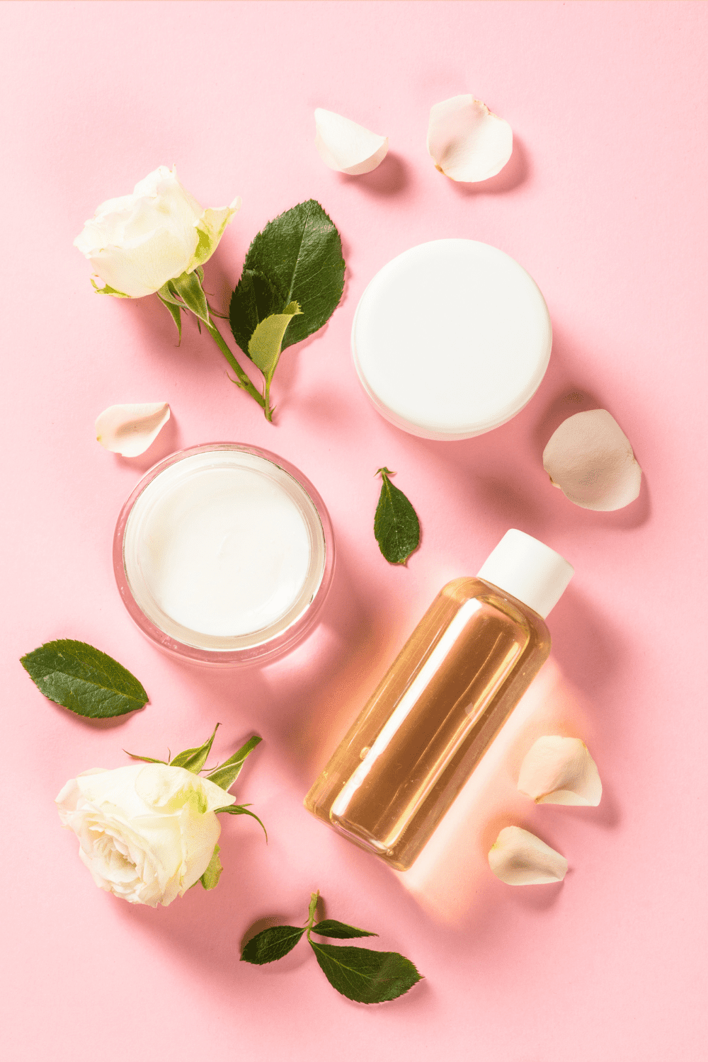 A picture of a pink background with roses, lotion, and oil.