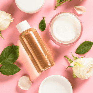 A picture of a pink background with roses, lotion, and oil.