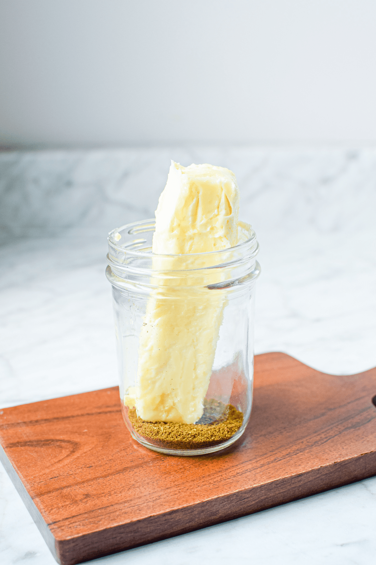 A picture of a jar of cannabutter with a stick of butter inside.