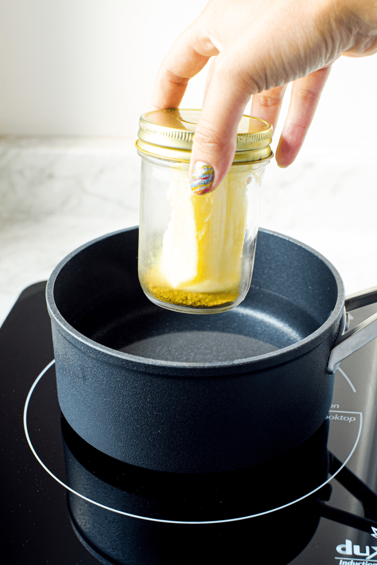 A picture of a jar of cannabutter with a stick of butter inside.