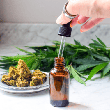 A hand with a cannabis tincture bottle.
