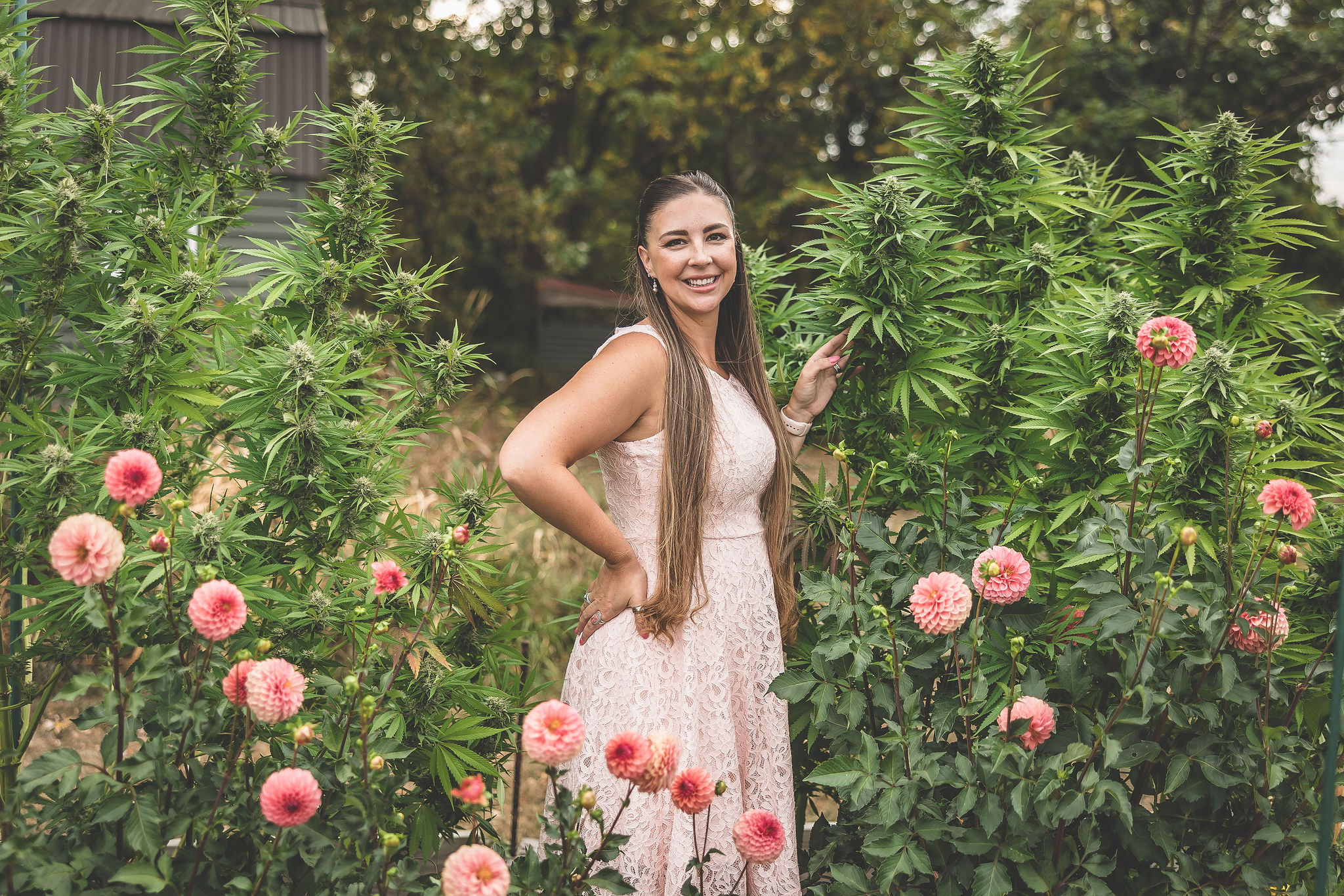 A picture of Emily Kyle in her garden with cannabis plants and dahlias.