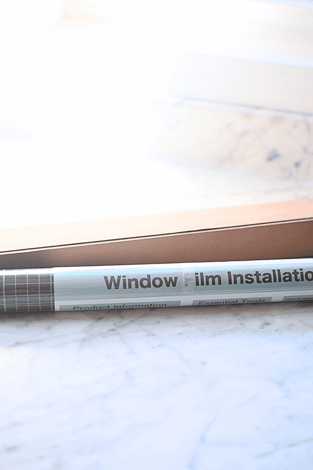 Window film installation rolled out on a white marble surface, illustrating home improvement and energy-efficient solutions.