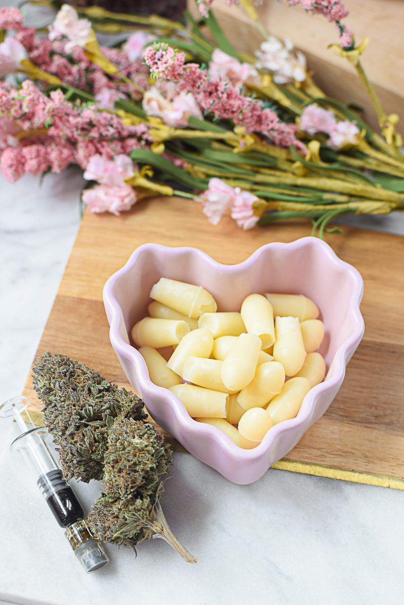 Cannabis suppository ingredients with herbs and coconut oil on wooden surface.